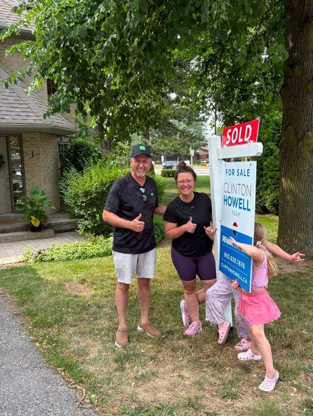 Happy clients give a thumbs up beside the Clinton Howell Team SOLD sign at 286 Hamilton Drive